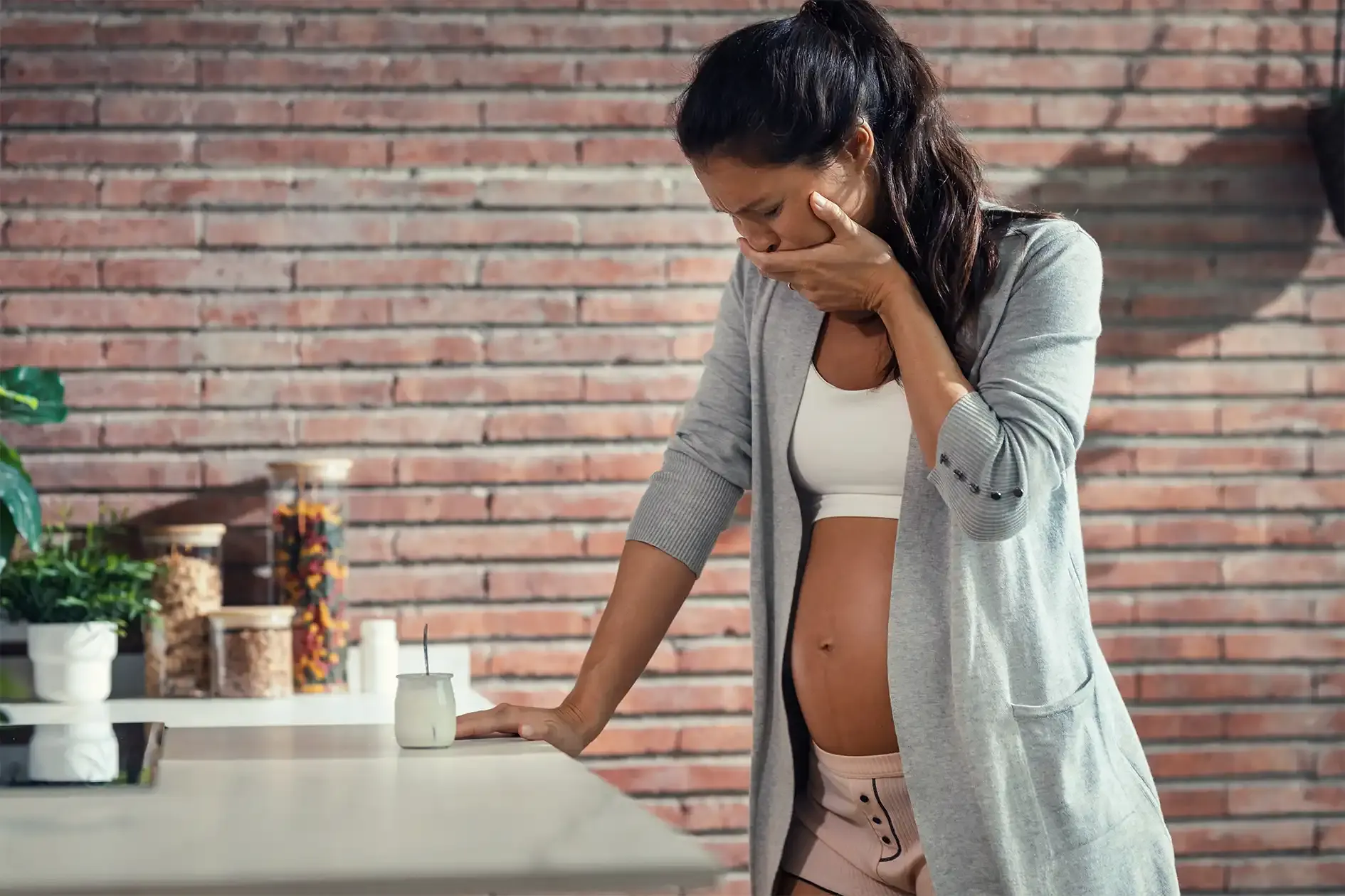 Woman with nausea leaning over against countertop