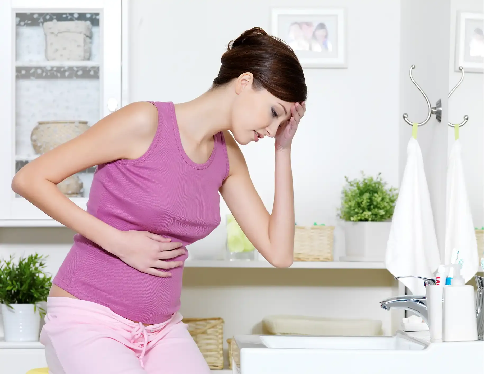 Woman with nausea leaning over against countertop